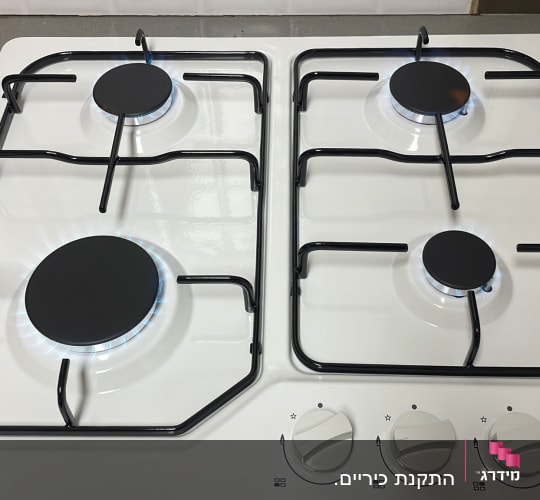 כיריים גז לבנות עם ארבעה מבערים דולקים
